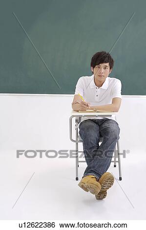 Young man sitting in the classroom and studying View Large Photo Image Stock Photograph - Young man sitting in the classroom and studying. Fotosearch