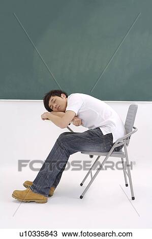 Stock Image - Young man sitting on the chair and sleeping. Fotosearch