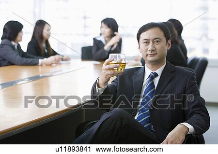 Stock Image - Business people holding a cup of drink and looking at the camera. Fotosearch