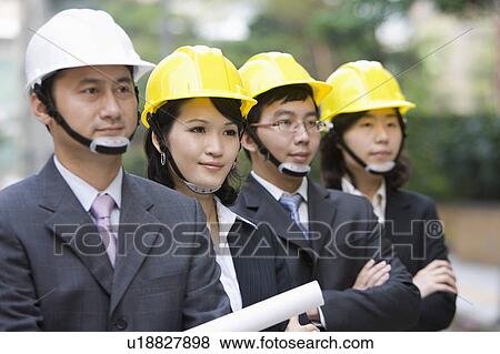 Stock Photo - Business people standing with helmets in a row. Fotosearch