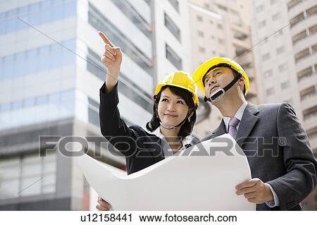Businessman and businesswoman looking away with helmets View Large Photo Image Stock Image - Businessman and businesswoman looking away with helmets. Fotosearch