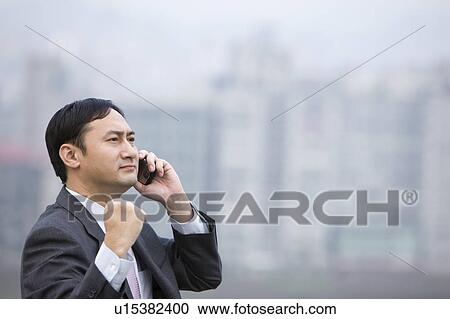 Businessman looking away with one fist up and on the phone View Large Photo Image Stock Image - Businessman looking away with one fist up and on the phone. Fotosearch
