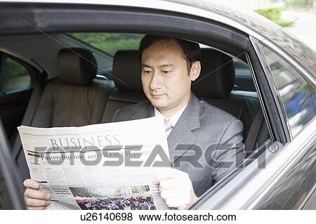 Stock Photo - Businessman reading newspaper in the car. Fotosearch