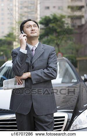 Businessman waiting with vehicle and using mobile phone View Large Photo Image Stock Photograph - Businessman waiting with vehicle and using mobile phone. Fotosearch