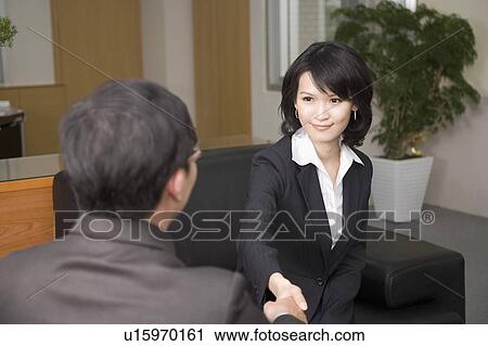Stock Image - Businesswoman and businessman shaking hands together. Fotosearch