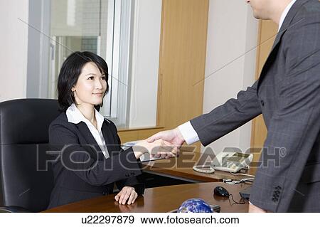 Stock Photo - Businesswoman and businessman shaking hands together. Fotosearch