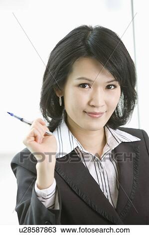 "Businesswoman holding a pen and looking at the camera, portrait" View Large Photo Image Stock Image - "Businesswoman holding a pen and looking at the camera, portrait". Fotosearch
