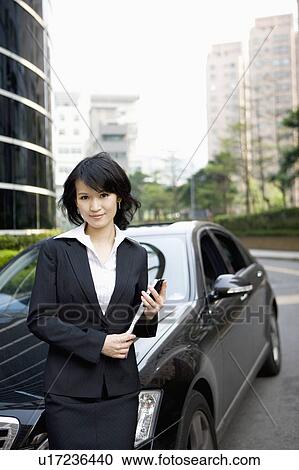 Businesswoman holding document folder and standing with vehicle View Large Photo Image Stock Image - Businesswoman holding document folder and standing with vehicle. Fotosearch