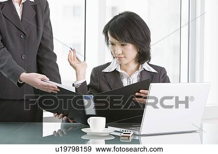 Businesswoman looking at document folder View Large Photo Image Stock Photo - Businesswoman looking at document folder. Fotosearch