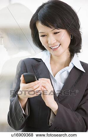 Stock Photo - "Businesswoman using mobile phone and smiling happily, portrait". Fotosearch