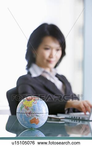 Businesswoman working with a globe on the desk View Large Photo Image Stock Photograph - Businesswoman working with a globe on the desk. Fotosearch
