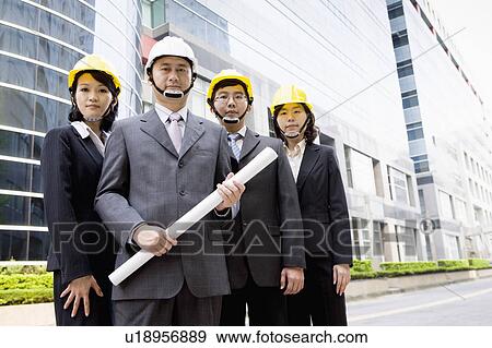 Four business people standing together with helmets View Large Photo Image Stock Photo - Four business people standing together with helmets. Fotosearch