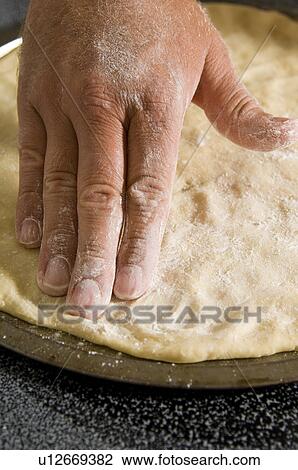 Stock Image - Man spreading pizza dough. Fotosearch