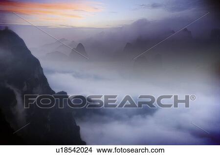 Mountain peaks above the clouds, with pink clouds in the horizon View Large Illustration Stock Illustration - Mountain peaks above the clouds, with pink clouds in the horizon. Fotosearch