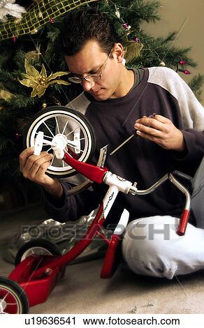 Stock Image - Dad assembling tricycle. Fotosearch