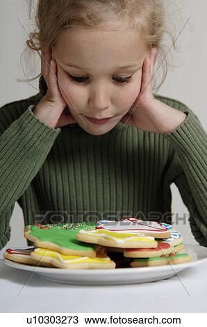 Girl looking at Christmas cookies on a plate View Large Photo Image Stock Image - Girl looking at Christmas cookies on a plate. Fotosearch