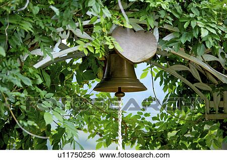 Stock Photograph - Arch door with bell entwined by plants, close-up. Fotosearch