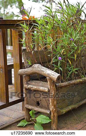 Stock Image - Plants in wooden pot by rail. Fotosearch