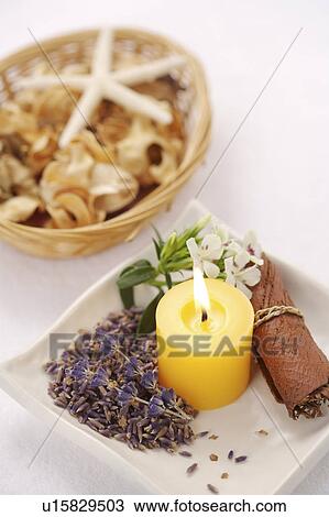 Stock Image - A burning aroma candle with some dry flowers. Fotosearch