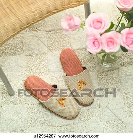 Stock Photo - Slippers on carpet with roses by its side, elevated view. Fotosearch