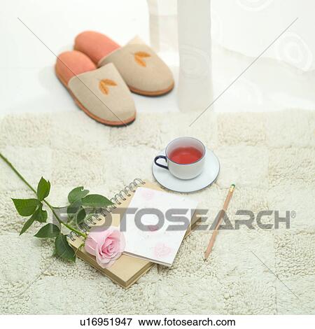 Stock Photo - Slippers, teacup, notebook, pencil, and a rose on carpet. Fotosearch