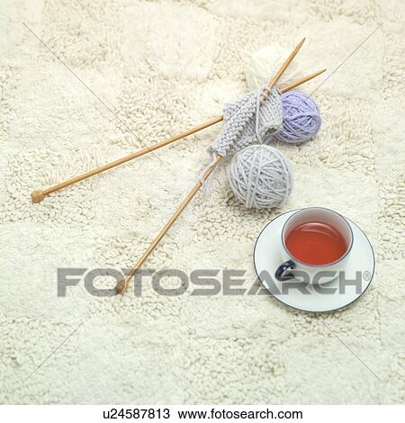 Stock Image - Teacup, knitting needles and wool balls. Fotosearch