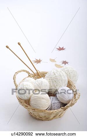 Stock Image - Wool balls and knitting needles in a basket. Fotosearch