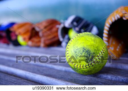 Stock Image - Baseball gloves and ball on bench. Fotosearch