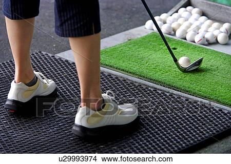 A woman hitting golf balls at a driving range View Large Photo Image Picture - A woman hitting golf balls at a driving range . Fotosearch