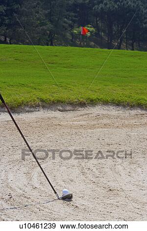 Stock Photo - Close-up of a golf club and a golf ball in sand trap . Fotosearch