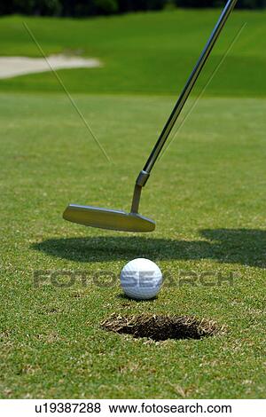 Golf ball and putter on edge of hole, close up View Large Photo Image Stock Photo - Golf ball and putter on edge of hole, close up . Fotosearch