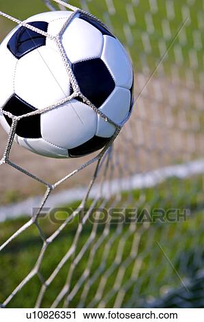 Stock Image - Close-Up of a Football Trapped in a Goal Net on a Football Pitch . Fotosearch