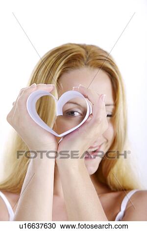 Stock Image - Young woman holding heart shaped object. Fotosearch