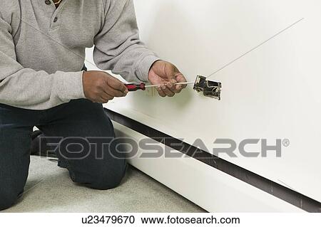 Stock Image - African American man working on a household receptacle, Vancouver, BC. Fotosearch