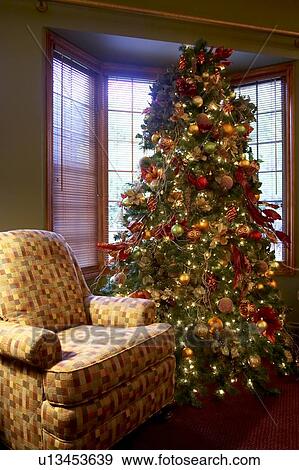 Decorated Christmas tree nestled by the window next to an armchair, Canada, Ontario View Large Photo Image Stock Photo - Decorated Christmas tree nestled by the window next to an armchair, Canada, Ontario. Fotosearch
