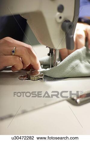 Stock Image - Detail of hands sewing fabric on a sewing machine, Canada, Ontario. Fotosearch
