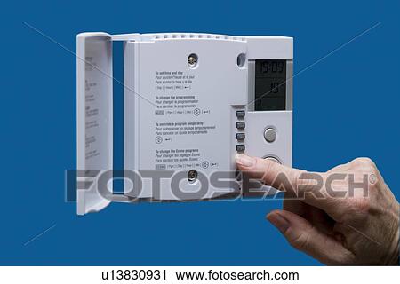 Stock Image - Hand changing thermostat. Fotosearch