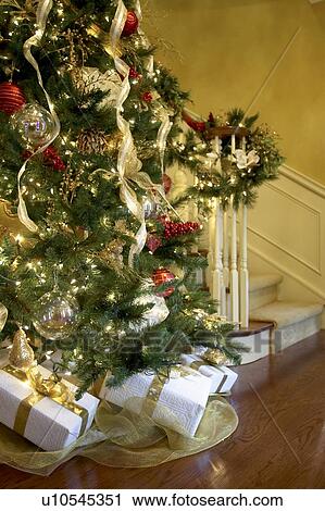 Stock Image - Presents under a Christmas tree at the base of a staircase, Canada, Ontario. Fotosearch