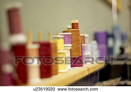 Stock Image - Spools of thread lined along the wall on a shelf, Canada, Ontario. Fotosearch
