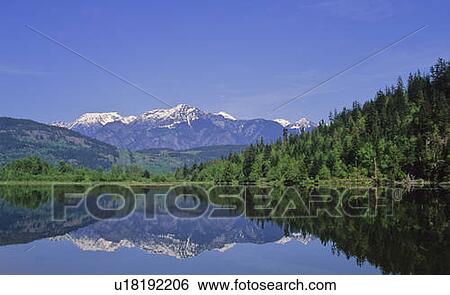 Stock Photograph - Cayoosh Mountain Range in reflected in One Mile Lake, near Pemberton. Fotosearch