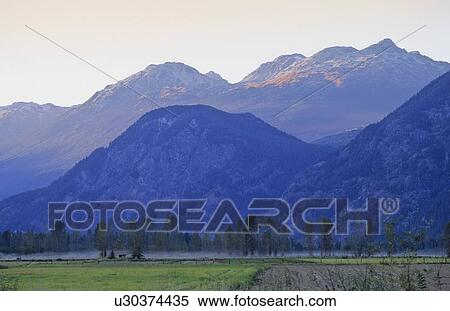 Stock Photography - Mountains rise in late summer day above Pemberton Valley. Fotosearch