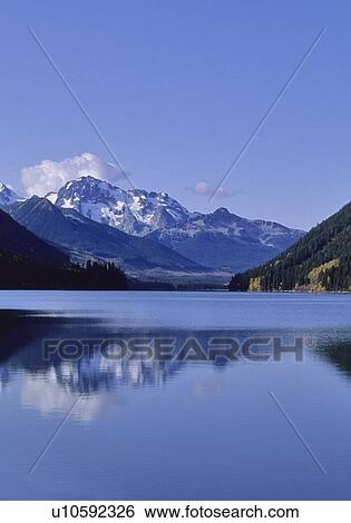Stock Photograph - The mountains above Carpenter Lake are reflected in early winter, B. C.. Fotosearch