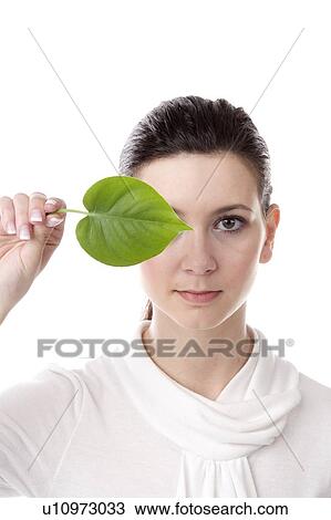 face of a young woman with a leaf held covering one eye View Large Photo Image Stock Image - face of a young woman with a leaf held covering one eye. Fotosearch