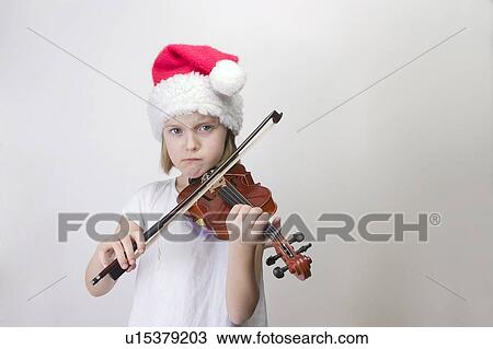 Stock Image - Girl - 6 years old playing violin in Santa hat. Fotosearch