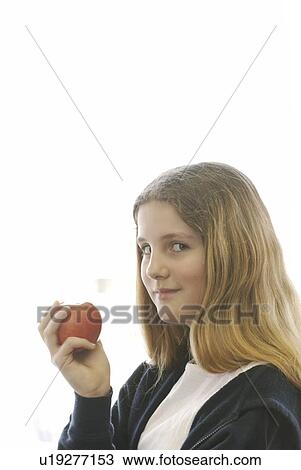Stock Image - Pre-teen girl eating organic apple, wearing hoodie made with hemp fibre, Canada, Manitoba, Brandon. Fotosearch
