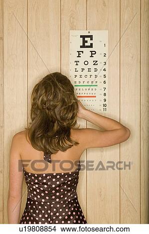 Young woman covers eye facing eye-test chart View Large Photo Image Picture - Young woman covers eye facing eye-test chart. Fotosearch