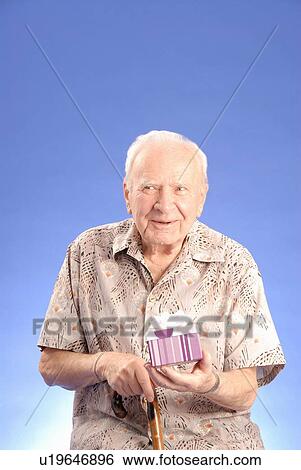 Stock Photograph - Senior male sitting with gift, Regina, Saskatchewan. Fotosearch