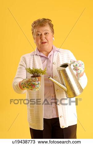 Stock Image - Senior Woman with plants; Canada, Saskatchewan, Regina. Fotosearch