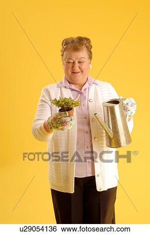 Stock Photograph - Senior Woman with plants; Canada, Saskatchewan, Regina. Fotosearch