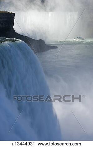 Stock Image - The American Falls with Horseshoe Falls and the Maid of the Mist in the Background - Niagara Falls, New York, USA. Fotosearch